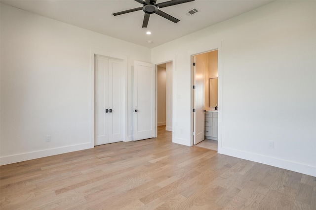 unfurnished bedroom featuring a closet, connected bathroom, light hardwood / wood-style floors, and ceiling fan