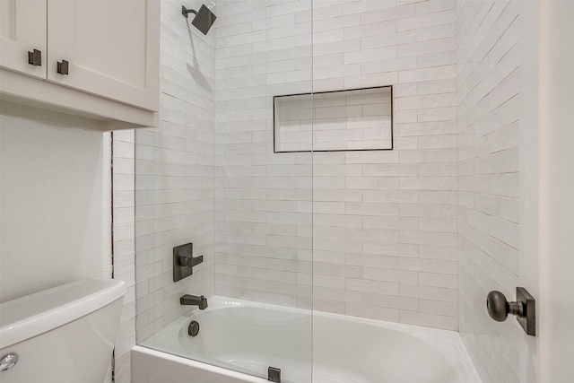 bathroom with tiled shower / bath combo and toilet