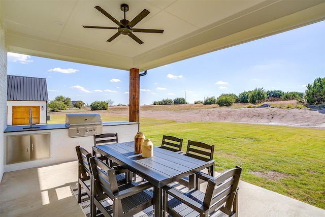 view of patio / terrace with an outdoor kitchen, sink, ceiling fan, a grill, and a rural view