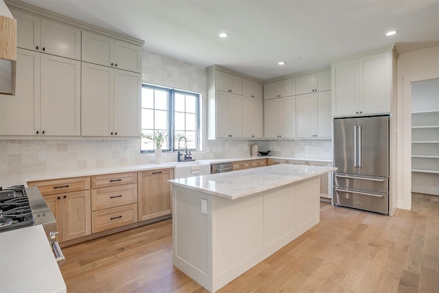 kitchen with a center island, light hardwood / wood-style floors, light stone counters, and stainless steel appliances