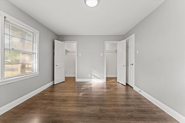 unfurnished bedroom with a walk in closet and dark hardwood / wood-style floors