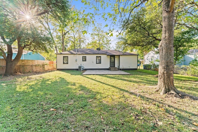 rear view of property featuring cooling unit, a lawn, and a patio