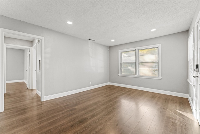 spare room featuring dark hardwood / wood-style flooring and a textured ceiling