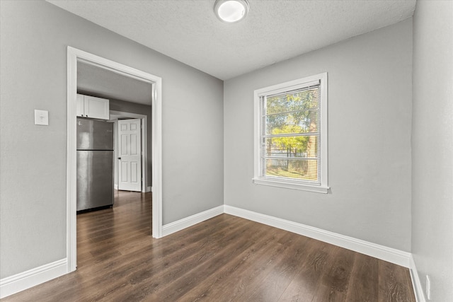 empty room featuring dark wood-type flooring and a textured ceiling