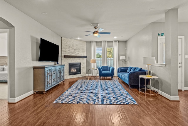 living room with a stone fireplace, hardwood / wood-style floors, and ceiling fan