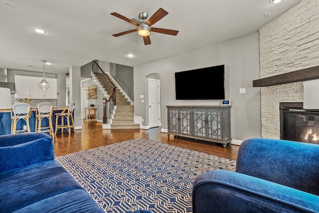 living room featuring ceiling fan, dark hardwood / wood-style flooring, and a fireplace