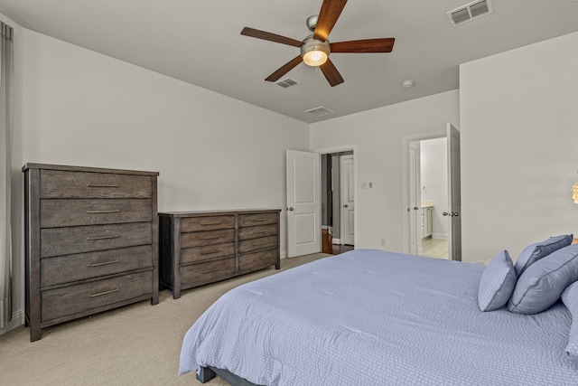 bedroom with ensuite bathroom, light colored carpet, and ceiling fan