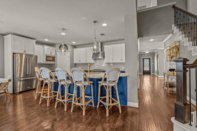 kitchen with appliances with stainless steel finishes, white cabinets, light stone countertops, and dark hardwood / wood-style flooring