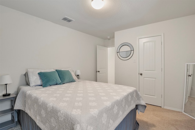 bedroom featuring a textured ceiling and light colored carpet