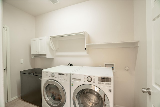 laundry room featuring washing machine and clothes dryer, light tile patterned floors, and cabinets