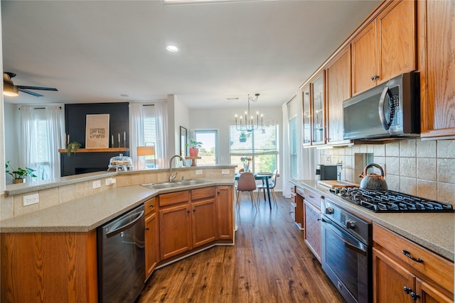 kitchen with dark hardwood / wood-style flooring, ceiling fan with notable chandelier, stainless steel appliances, sink, and pendant lighting