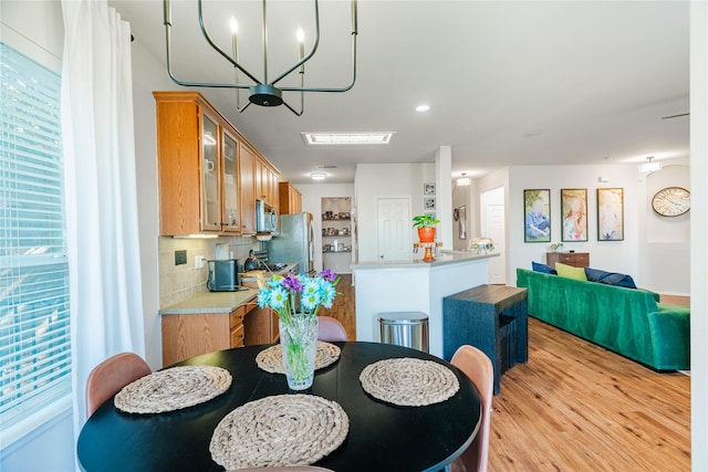 dining space with a notable chandelier, light wood-type flooring, and a wealth of natural light