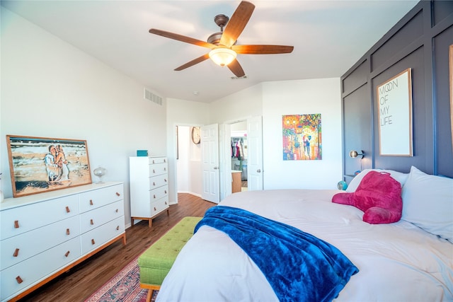 bedroom featuring ceiling fan, dark hardwood / wood-style flooring, a walk in closet, and a closet