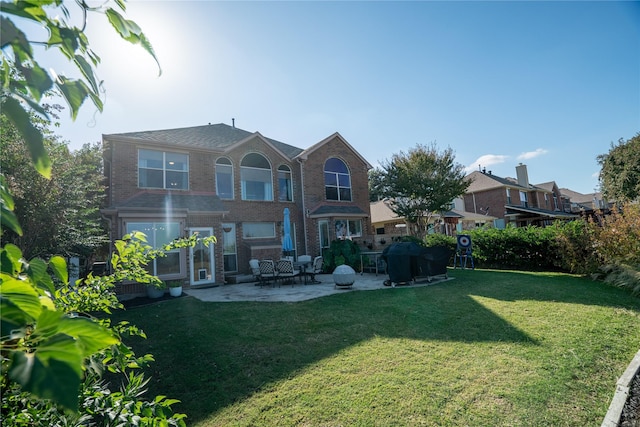 back of property featuring a yard, brick siding, and a patio