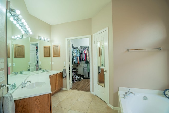 bathroom with tile patterned flooring, vanity, and a bath