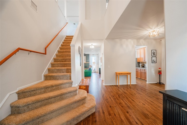 stairway with hardwood / wood-style floors and a towering ceiling