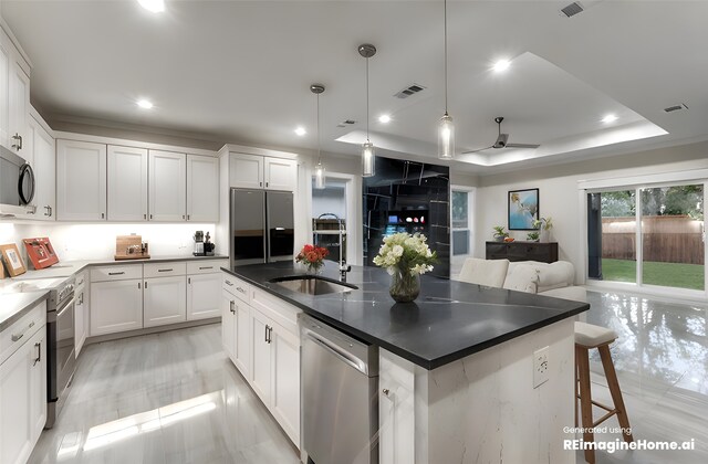 kitchen featuring white cabinets, a center island with sink, stainless steel appliances, decorative light fixtures, and sink