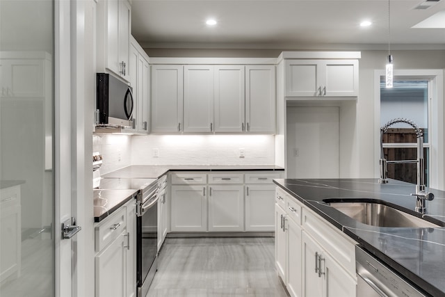 kitchen featuring appliances with stainless steel finishes, hanging light fixtures, and white cabinets