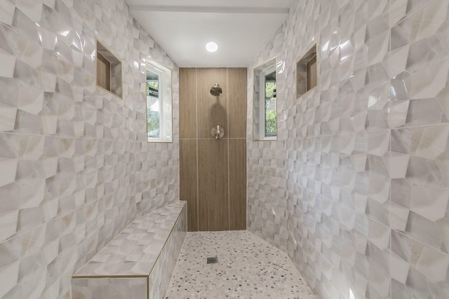 bathroom with tiled shower and tile walls