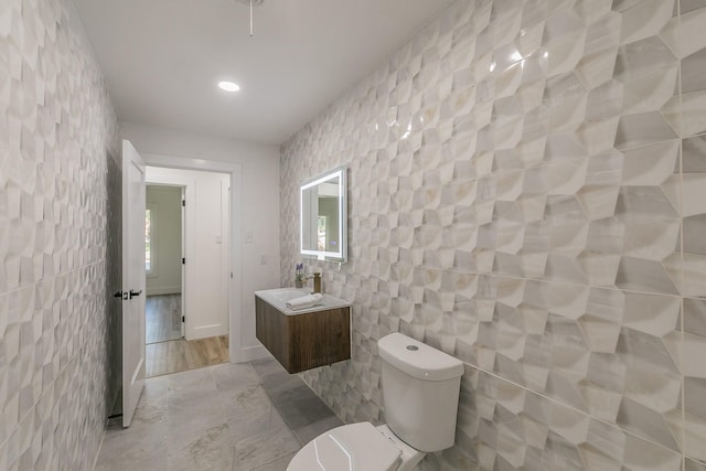 bathroom with tile walls, toilet, and vanity