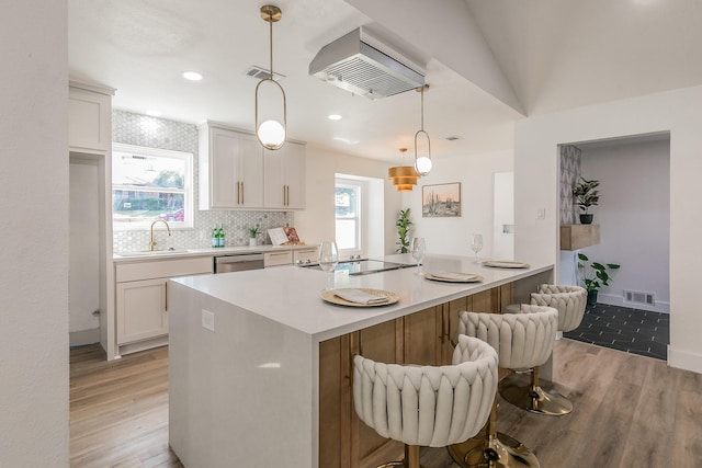 kitchen with light hardwood / wood-style flooring, decorative light fixtures, black electric stovetop, white cabinetry, and sink