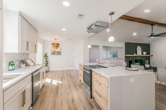 kitchen with white cabinets, beamed ceiling, pendant lighting, a kitchen island with sink, and appliances with stainless steel finishes