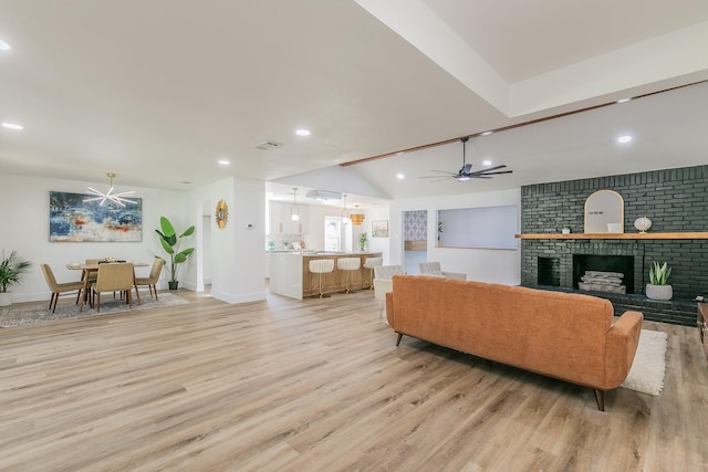 living room with light hardwood / wood-style floors, ceiling fan, a brick fireplace, and lofted ceiling