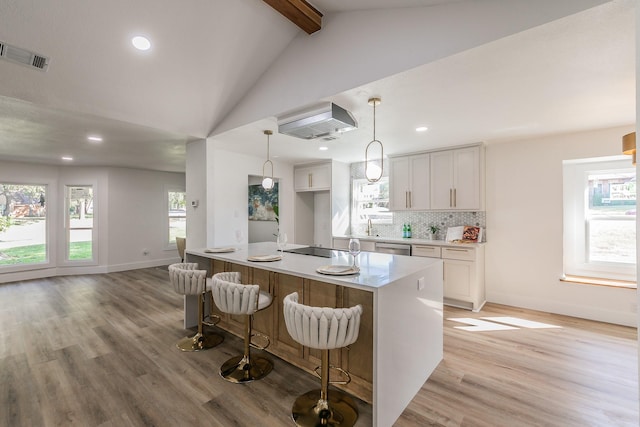 kitchen with light hardwood / wood-style floors, vaulted ceiling with beams, pendant lighting, white cabinets, and backsplash