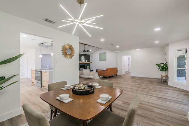 dining area with ceiling fan with notable chandelier, vaulted ceiling, and light hardwood / wood-style flooring