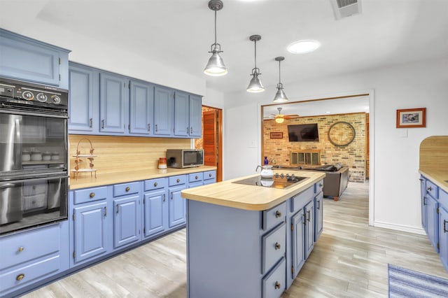 kitchen featuring hanging light fixtures, a kitchen island, blue cabinetry, light hardwood / wood-style flooring, and black appliances