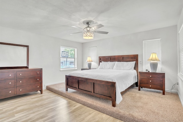 bedroom with light hardwood / wood-style flooring, a textured ceiling, and ceiling fan