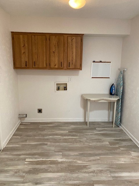 laundry area featuring hookup for an electric dryer, light hardwood / wood-style flooring, washer hookup, and cabinets