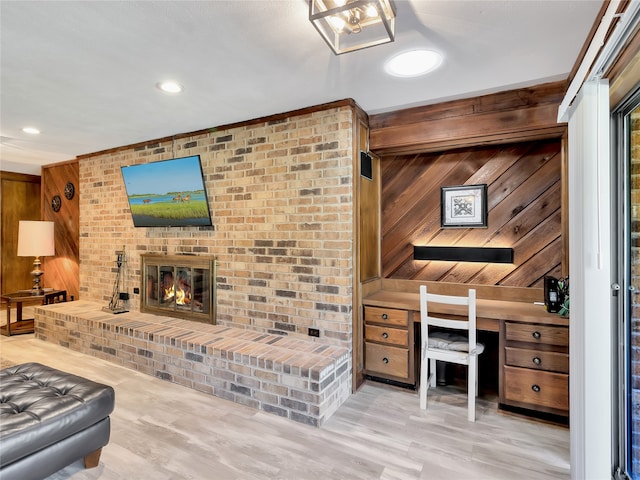 living room featuring a fireplace, wood walls, built in desk, and light wood-type flooring