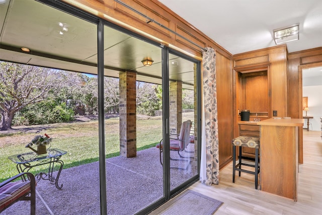 doorway to outside featuring wood walls and light wood-type flooring