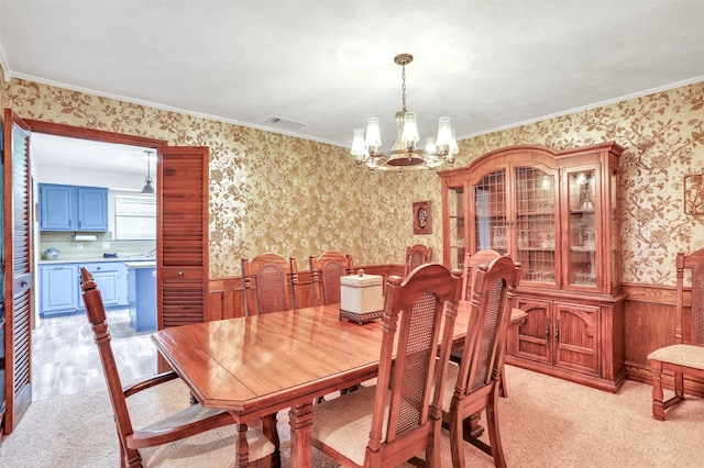 dining room featuring crown molding, a notable chandelier, light colored carpet, and wood walls