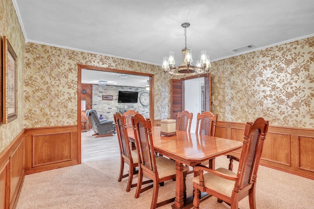 carpeted dining space with ornamental molding, an inviting chandelier, and wooden walls