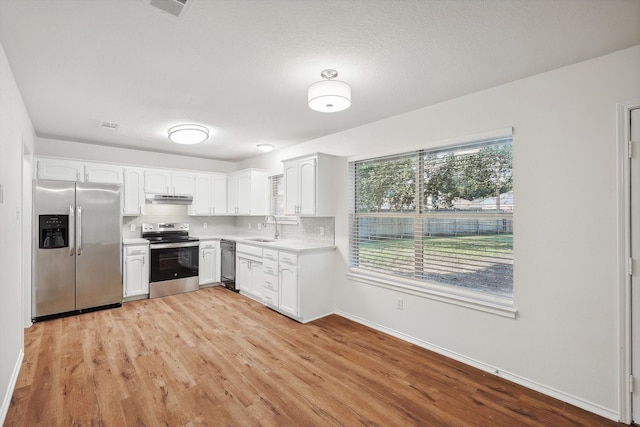 kitchen featuring sink, light hardwood / wood-style floors, stainless steel appliances, white cabinets, and decorative backsplash