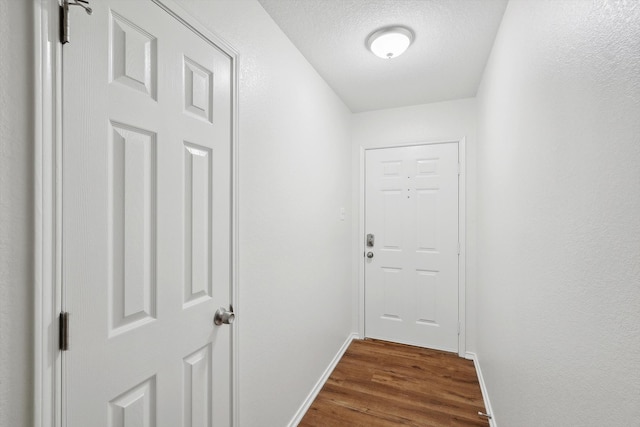 doorway to outside featuring dark wood-type flooring and a textured ceiling