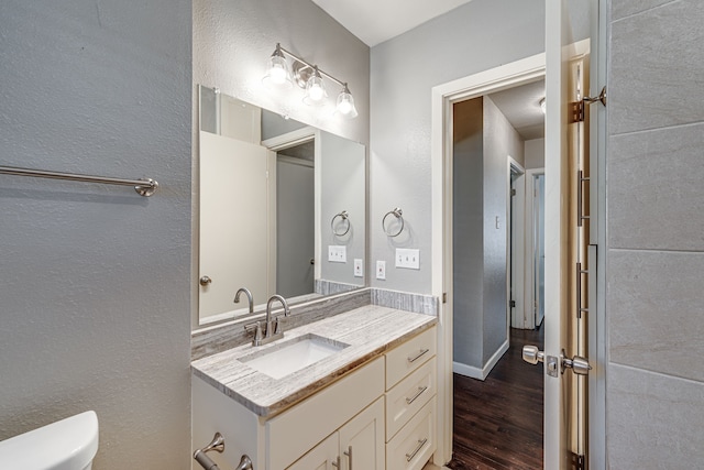 bathroom with vanity, toilet, and hardwood / wood-style flooring