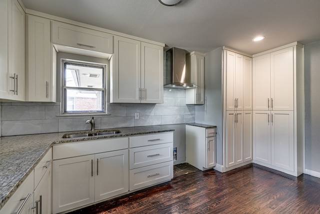 kitchen featuring wall chimney exhaust hood, sink, white cabinets, and dark wood-type flooring