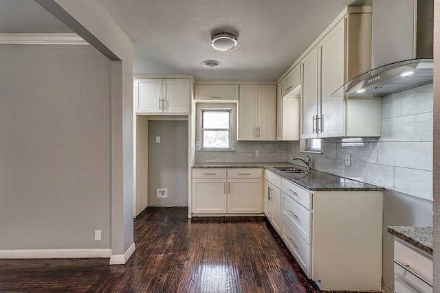 kitchen featuring white cabinetry, dark stone counters, dark hardwood / wood-style floors, wall chimney exhaust hood, and sink