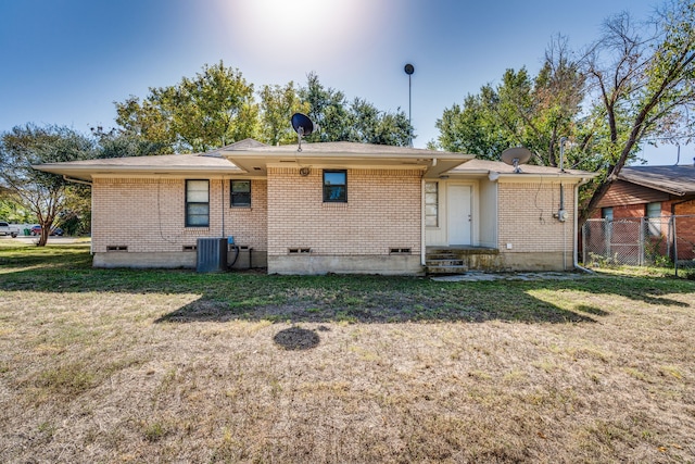 rear view of house with central AC and a lawn