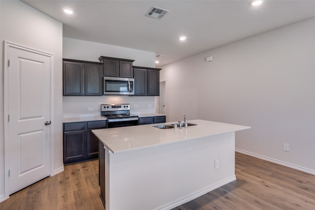 kitchen featuring sink, appliances with stainless steel finishes, hardwood / wood-style flooring, and an island with sink