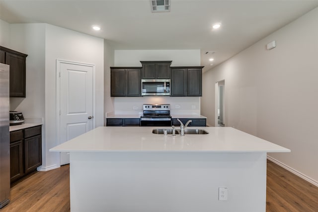 kitchen featuring sink, appliances with stainless steel finishes, wood-type flooring, and an island with sink