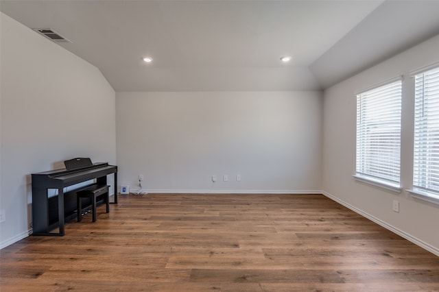 spare room with hardwood / wood-style flooring and lofted ceiling