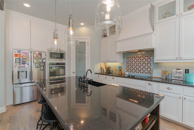 kitchen with light hardwood / wood-style floors, appliances with stainless steel finishes, sink, and a kitchen island with sink