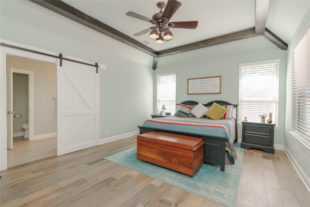 bedroom with connected bathroom, ceiling fan, light hardwood / wood-style flooring, and a barn door