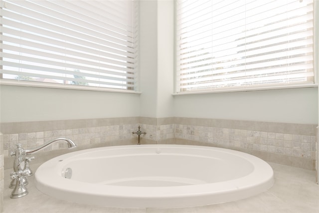 bathroom featuring a relaxing tiled tub and a healthy amount of sunlight