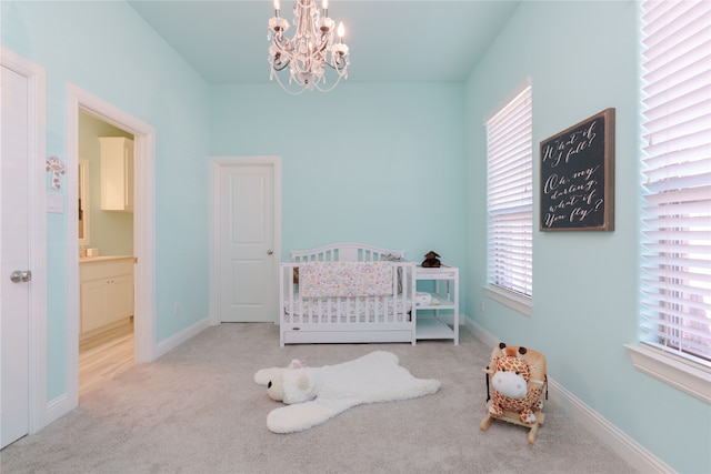 carpeted bedroom featuring an inviting chandelier, a crib, and connected bathroom