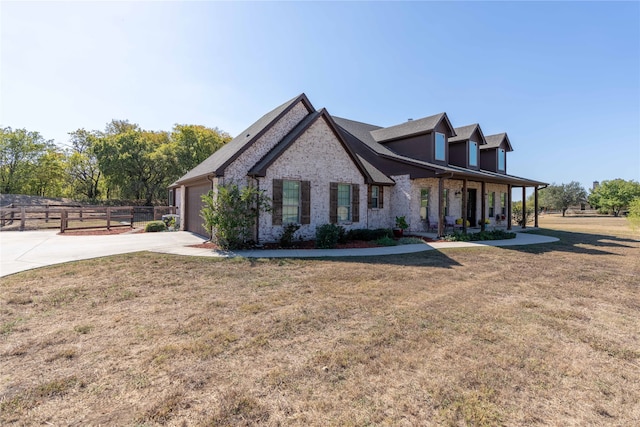 view of front of home with covered porch, a front lawn, and a garage